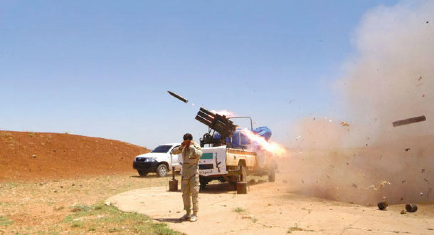 مقاتل من «الجيش السوري الحر» يحاول حماية أذنيه إثر إطلاق صواريخ على قوات النظام في بلدة أزرع التابعة لمحافظة درعا أمس (رويترز)