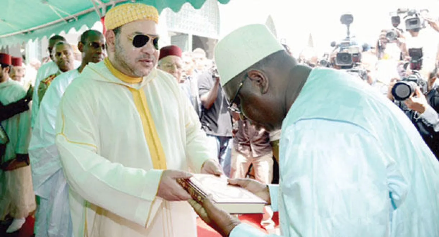 العاهل المغربي الملك محمد السادس أثناء إهدائه 10 آلاف نسخة من المصحف الشريف لمساجد السنغال (ماب)