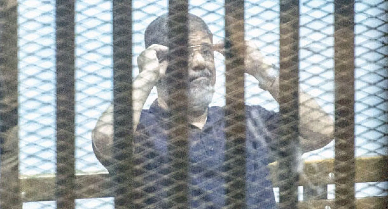 مرسي خلف القضبان أثناء النظر في قضية إهانة القضاء أمس (أ.ف.ب)