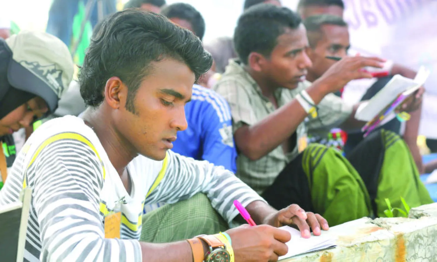 شبان من الروهينغا يتعلمون اللغة بعد إنقاذهم من البحر ونقلهم إلى مخيم مؤقت في إقليم آتشيه الإندونيسي أمس (أ.ب)