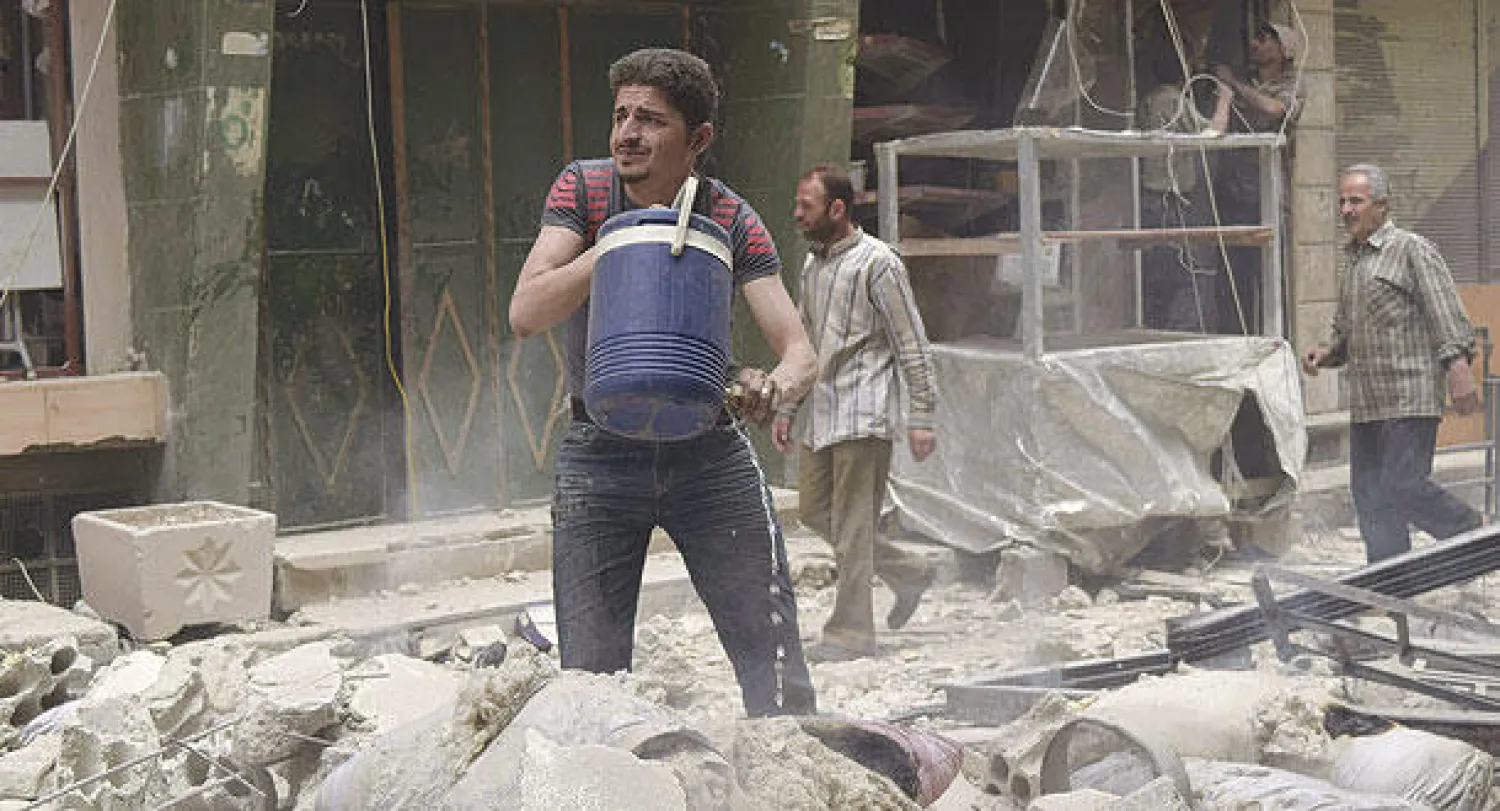 رجل من سكان عربين بريف دمشق يحاول إطفاء حريق في بيته نتج عن غارة جوية من طيران النظام (رويترز)