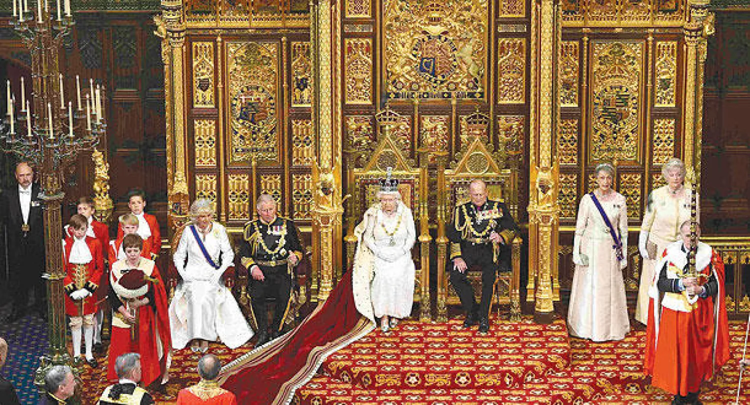 ملكة بريطانيا الملكة إليزابيث وإلى يسارها زوجها الأمير فيليب وإلى يمينها ولي العهد الأمير تشارلز قبل خطابها أمام أمس (رويترز)