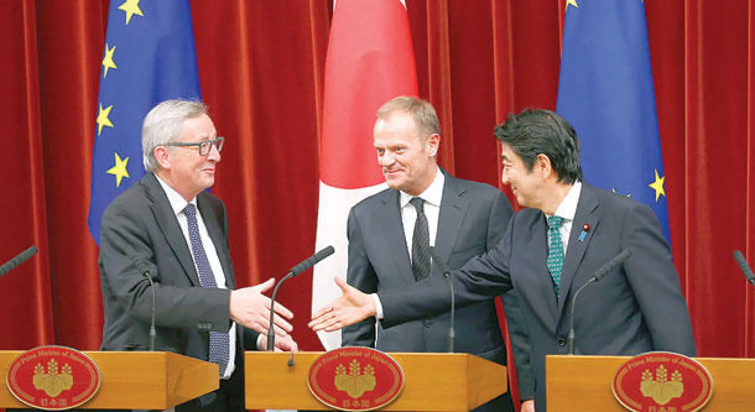 رئيس الوزراء الياباني شينزو آبي يصافح رئيس المفوضية الأوروبية جان كلود يونكر لدى إنجاز الاتفاق في طوكيو أمس (أ.ب)