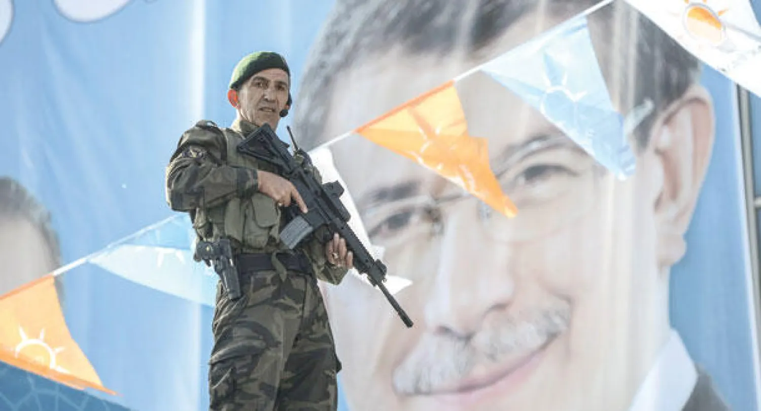 ضابط شرطة تركي يقف قرب ملصق انتخابي كبير لرئيس الحكومة التركية أحمد داود أوغلو في إسطنبول أمس (أ.ف.ب)