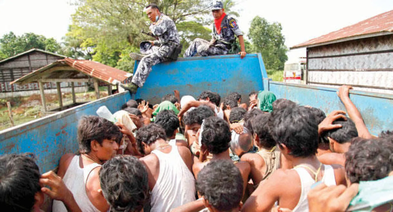 رجال أمن تابعون لدولة ميانمار أثناء نقلهم لمهاجرين إلى مخيم «مي تايك» المؤقت بضواحي بلدة مونغ داو القريبة من حدود بنغلاديش (إ.ب.أ)