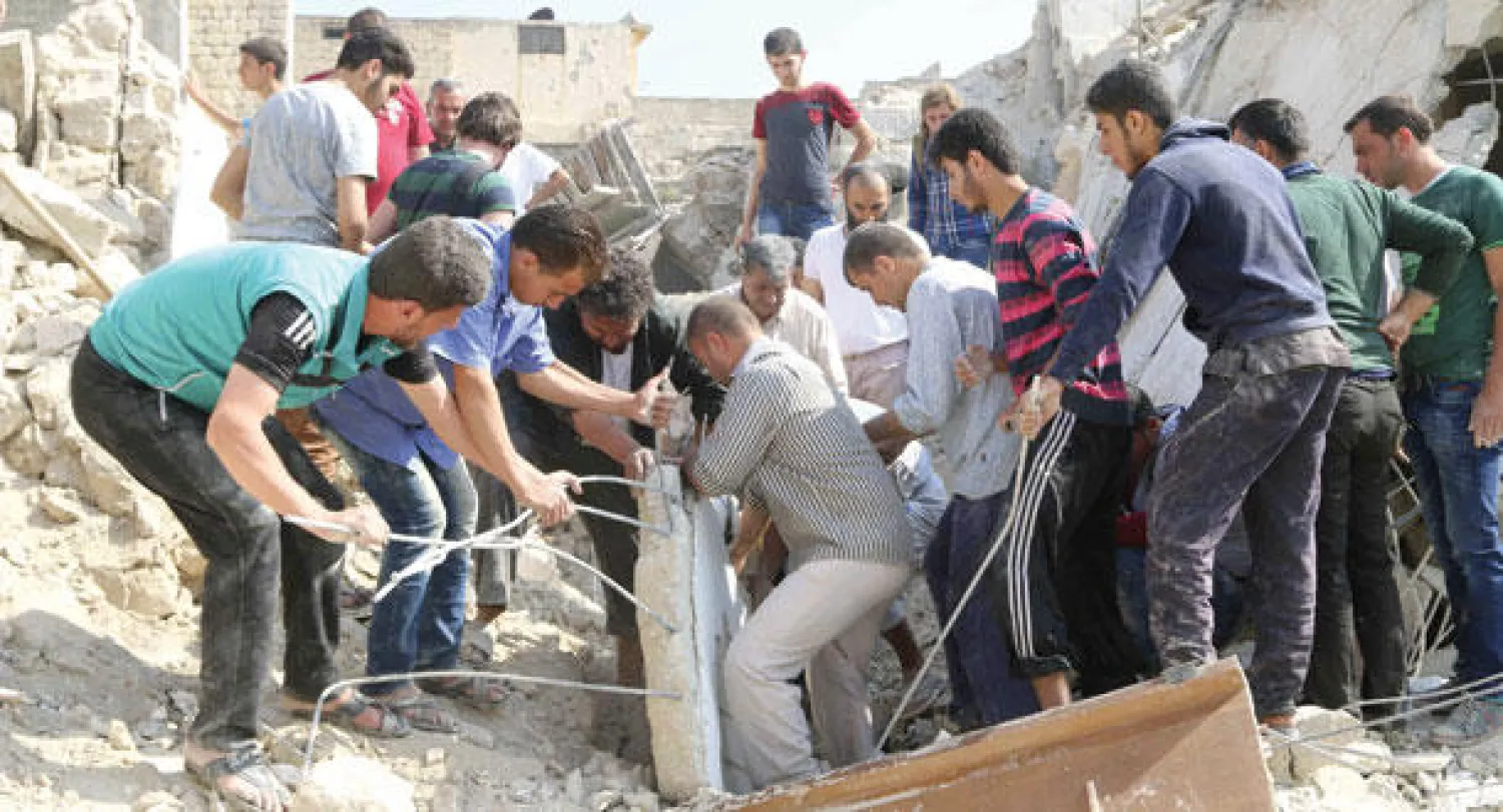 جمع من المواطنين السوريين والعاملين في الدفاع المدني يرفعون الركام لانتشال ضحايا قصف جوي بالبراميل المتفجرة على أحد أحياء حلب القديمة يوم أمس (رويترز)