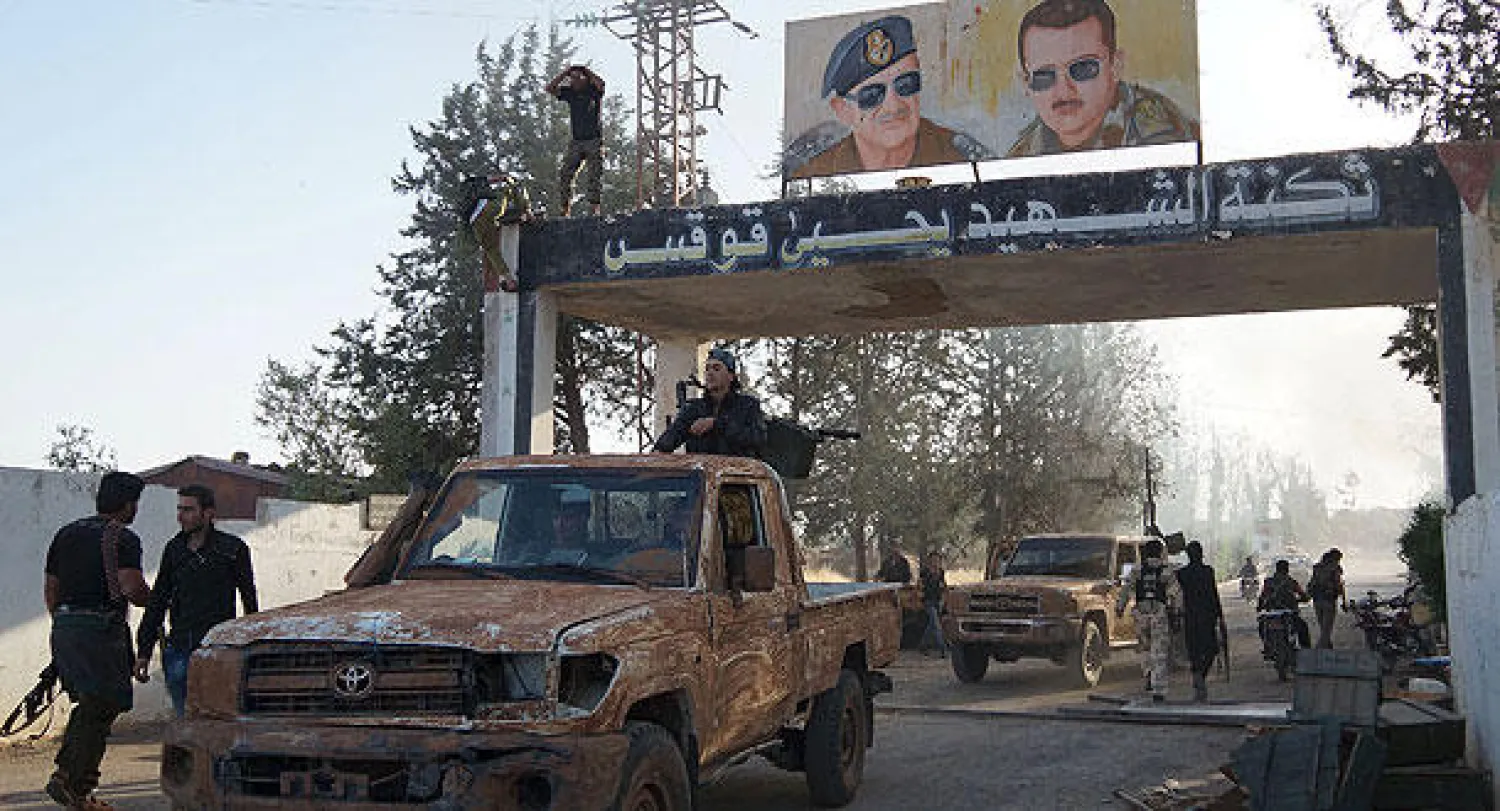 صورتا الأسد الأب والابن عند مدخل اللواء 52 الذي سيطرت عليه المعارضة أول من أمس (رويترز)