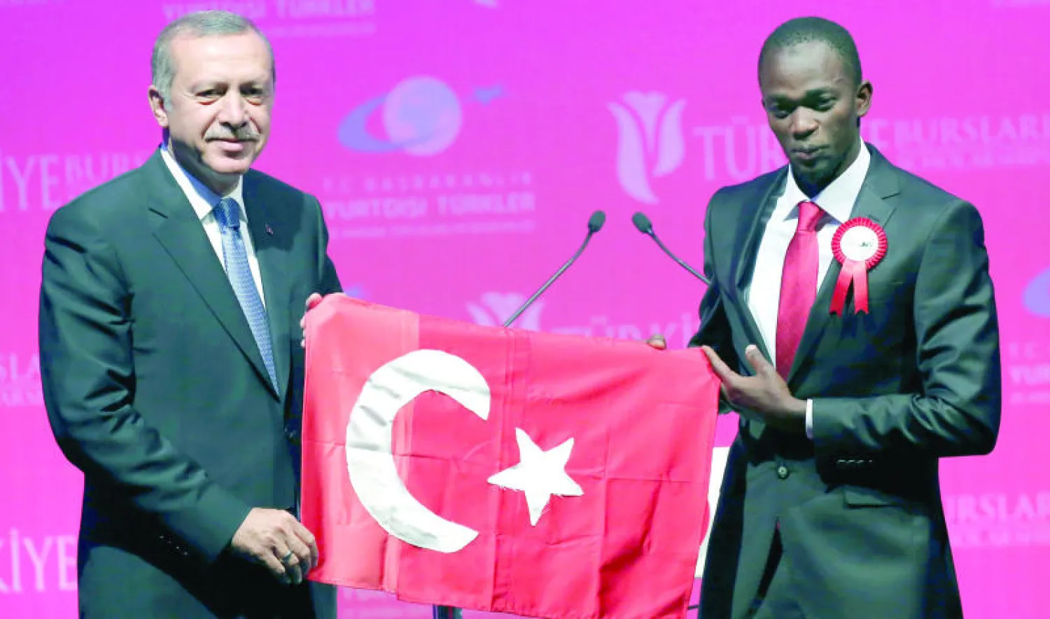 الرئيس التركي رجب طيب إردوغان يتسلم العلم التركي من طالب أوغندي أثناء تخريج دفعة من الطلبة المبتعثين في أنقرة أمس (أ.ب)