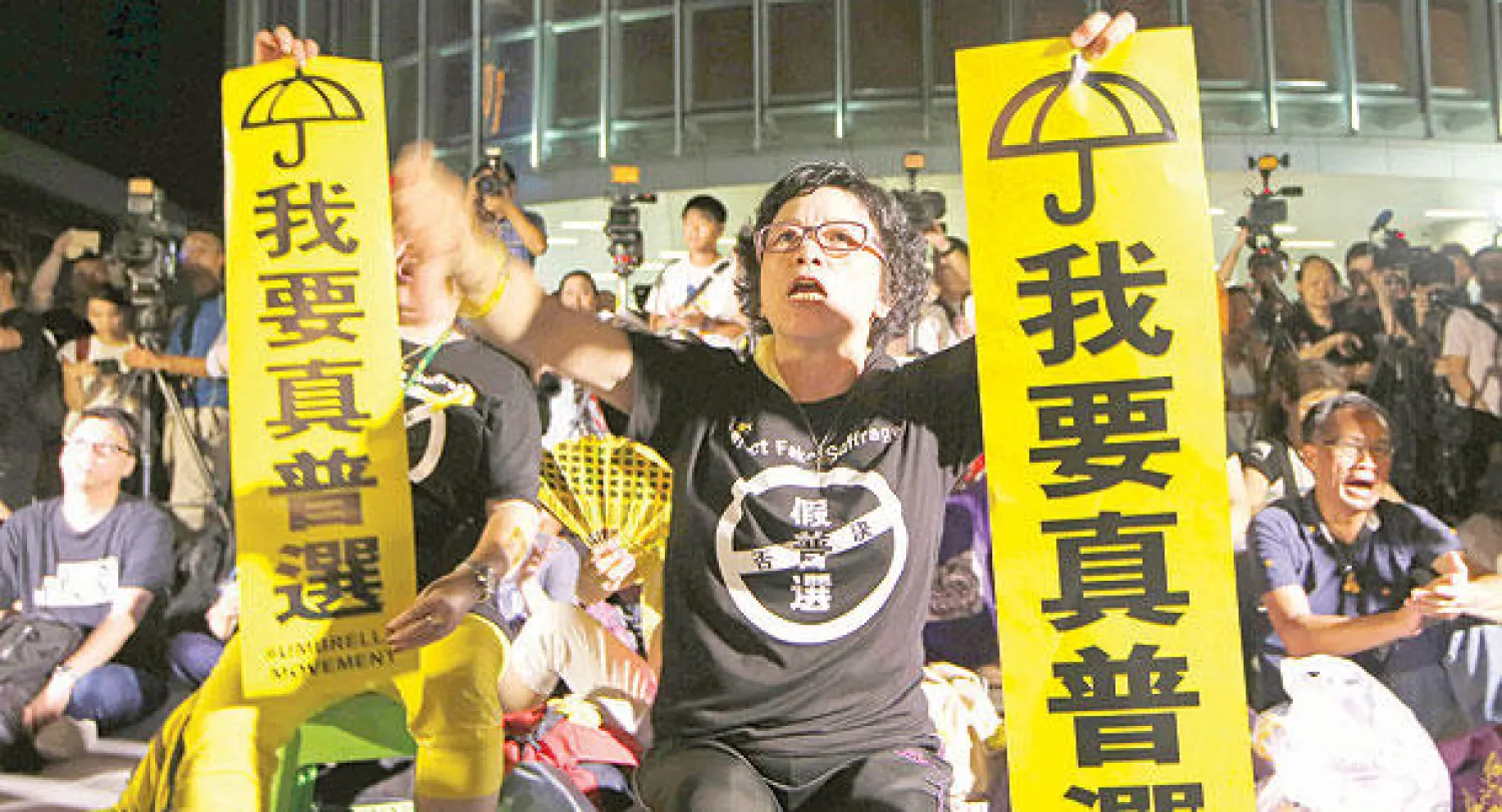 متظاهرون مؤيدون للديمقراطية في هونغ كونغ يحملون لافتات تقول: «أريد اقتراع العام الحقيقي» خلال مسيرة أمام المجلس التشريعي في هونغ كونغ أمس (أ.ب)