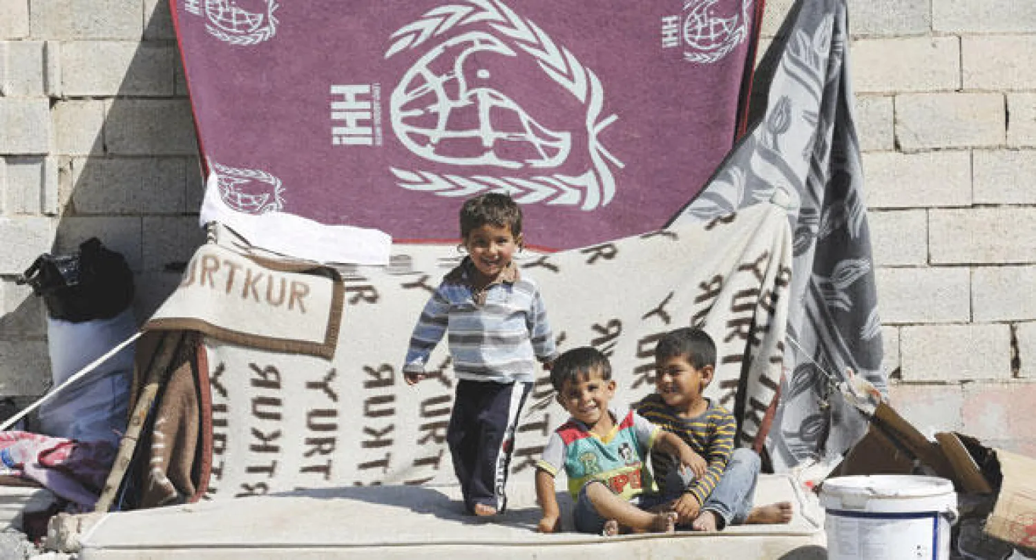 أطفال سوريون لاجؤن من بلدة تل أبيض الحدودية الشمالية يلعبون أمام خيمة في معسكر الإيواء على الجانب التركي من الحدود (رويترز)