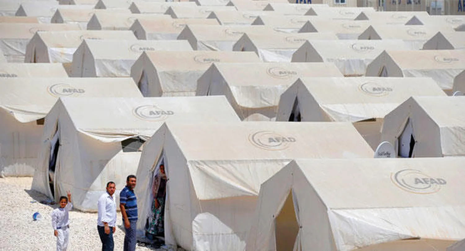 لاجئون سوريون يتمشون حول معسكر إيواء على الجانب التركي من الحدود السورية ـ التركية (أ.ب)