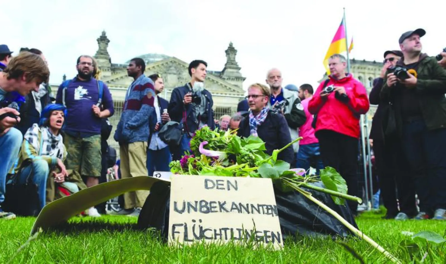 ناشطون ألمان أمام مبنى البرلمان يقفون أمام جنازة رمزية للاجئين المجهولين الذين قضوا أثناء محاولتهم الهروب من بلدانهم (أ.ف.ب)