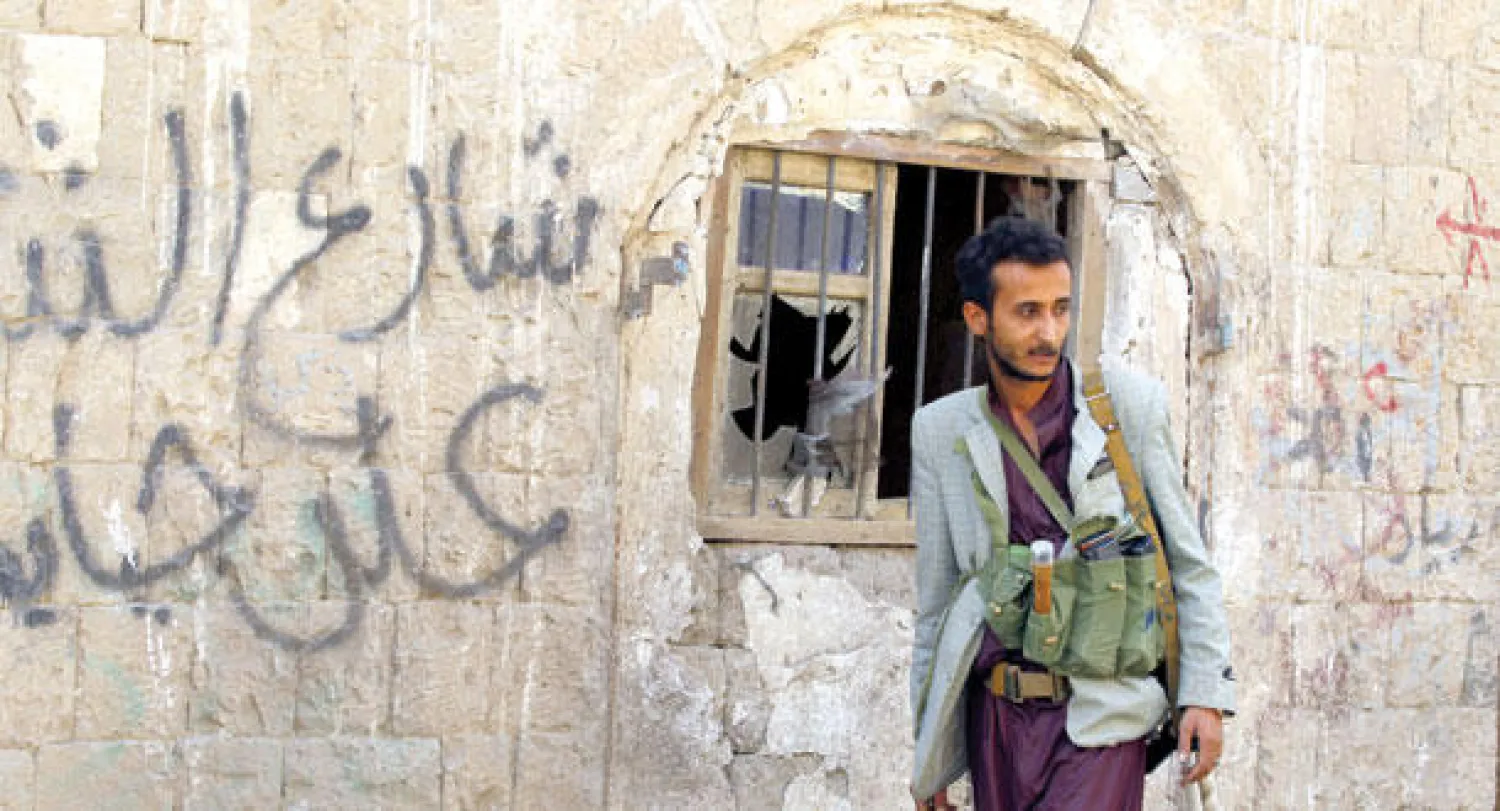 مسلح حوثي يجوب أحد أزقة صنعاء المحيطة بمكان الهجوم الذي شهدته العاصمة أمس (إ.ب.أ)