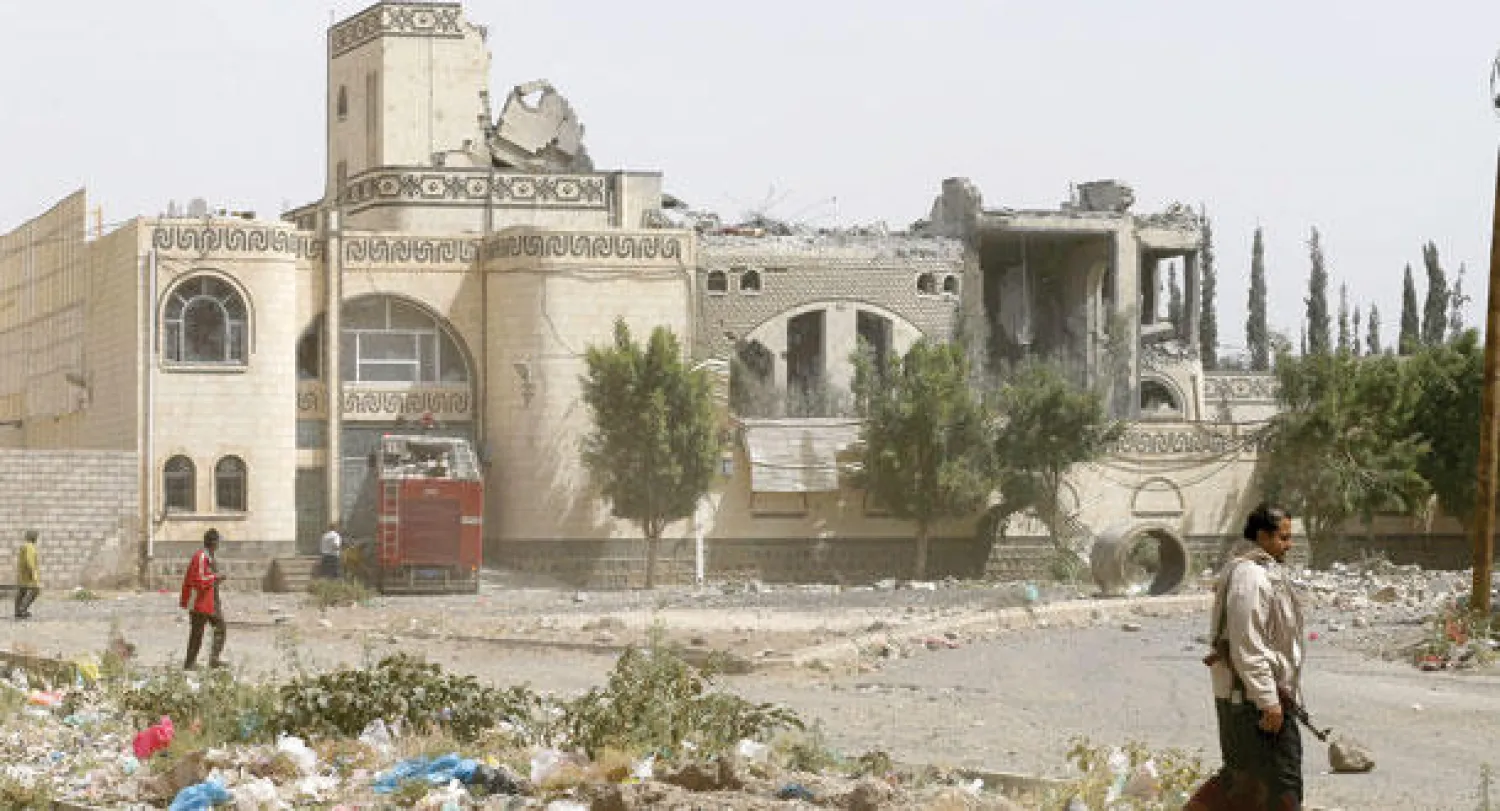 يمنيون يمشون إلى جانب بيت القيادي السابق علي الكهلاني في حكومة الرئيس السابق صالح في صنعاء أمس (رويترز)