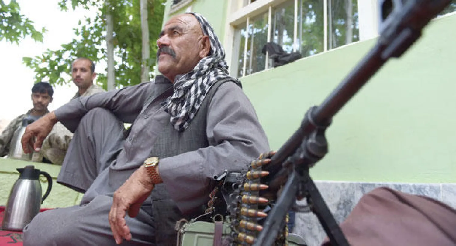 أحد زعماء الميليشيات الأفغانية الموالية للحكومة أمام مركز شرطة في قندز أمس (أ.ف.ب)