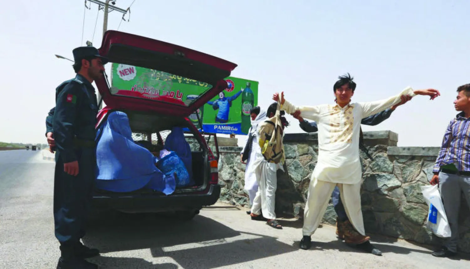 جندي أفغاني يفتش مواطنًا على الطريق السريع الذي يربط العاصمة الأفغانية كابل ومدينة هراة إثر تشكيل لجنة للتحقيق في مقتل عشرين شرطيًا بنيران طالبان خلال إحدى المعارك (إ.ب.أ)