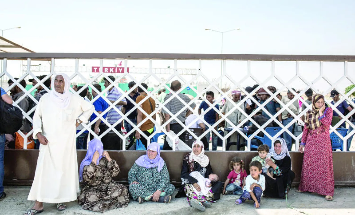 نازحون سوريون من تل أبيض هربوا من القتال بين الأكراد و«داعش» الشهر الماضي ينتظرون الدخول إلى الأراضي التركية (أ.ف.ب)