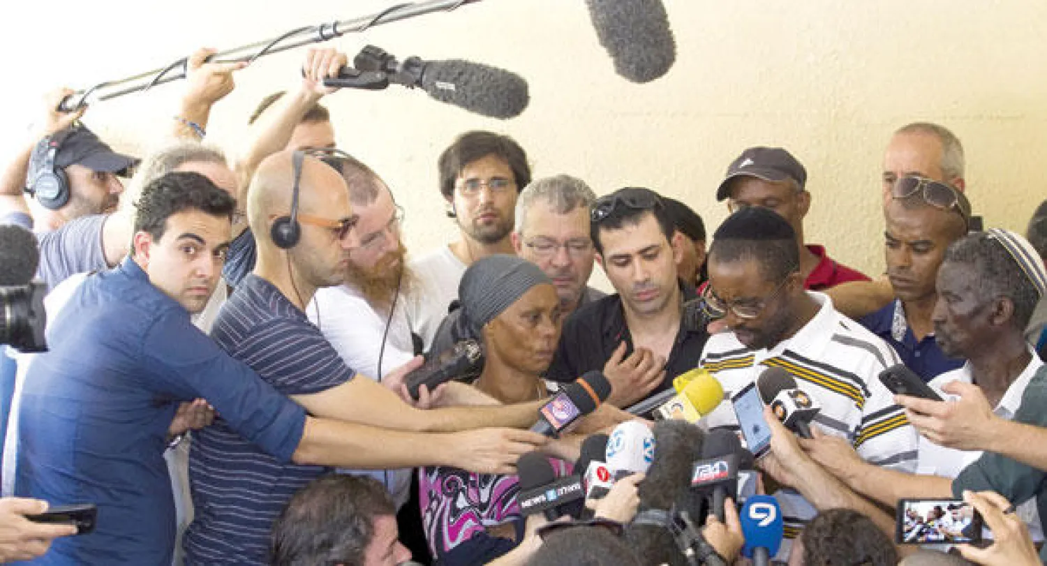 إيلان منغستو شقيق الجندي أفراهام الموجود لدى حماس يتحدث إلى وسائل الإعلام وبرفقته والدهما خارج منزلهما في مدينة عسقلان أمس (رويترز)