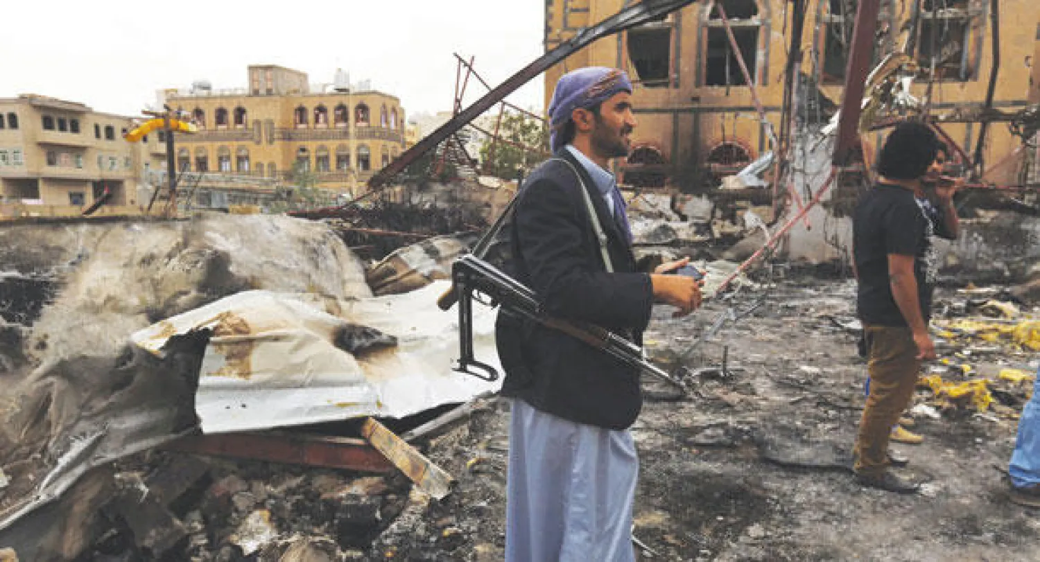 مسلحون يتفقدون الأضرار التي لحقت بالمباني الواقعة تحت سيطرة ميليشيات الحوثي وصالح في صنعاء جراء غارات جوية  لقوات التحالف (أ.ب)