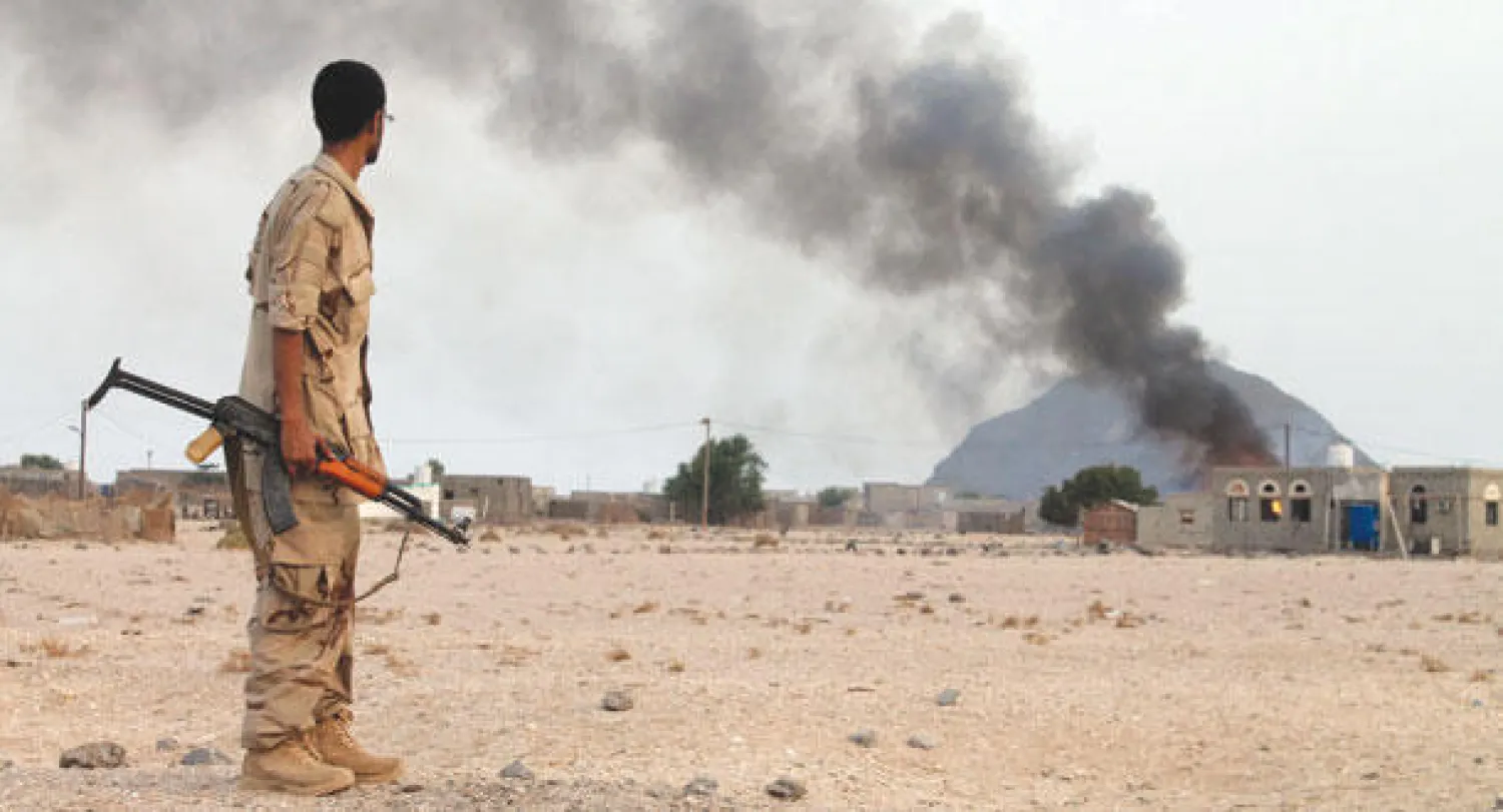 مقاتل يمني من لجان المقاومة الشعبية يراقب تصاعد سحب الدخان من مبنى هاجمته قوات عسكرية تابعة للحوثيين غرب مدينة عدن جنوب اليمن (أ.ف.ب)