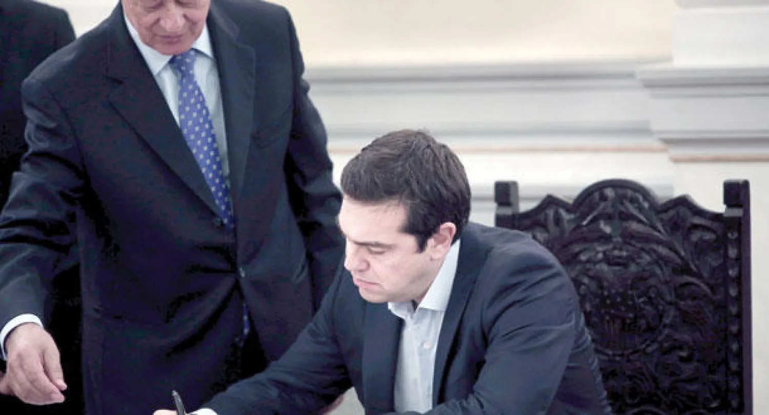 رئيس الوزراء اليوناني ألكسيس تسيبراس يوقع أوراق تثبيت وزراء جدد في حكومته بعد أدائهم اليمين الدستورية في القصر الرئاسي بأثينا أمس (أ.ف.ب)