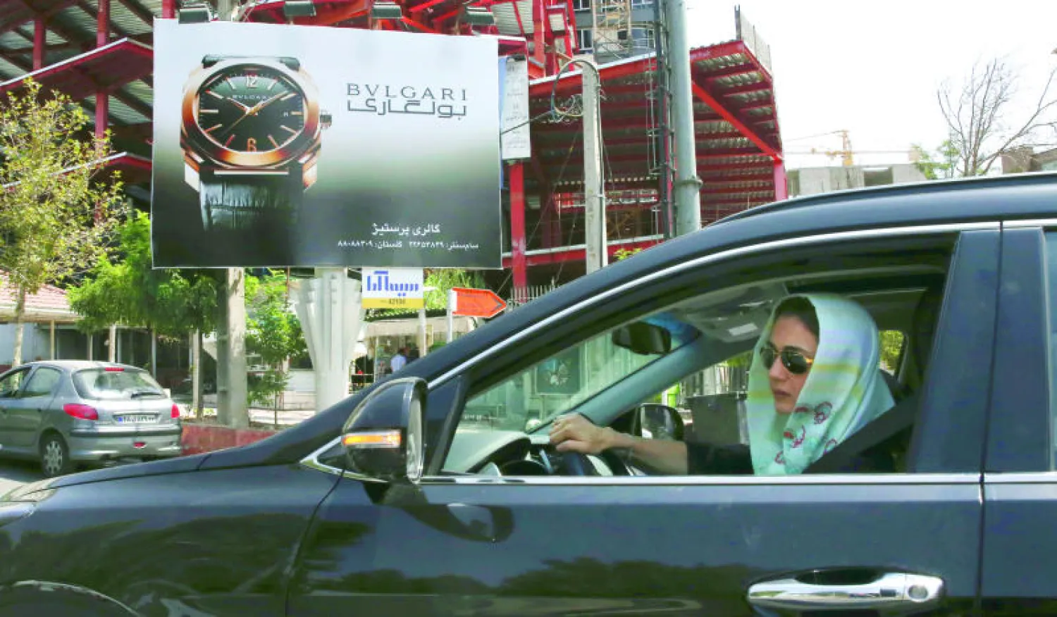 إيرانية تقود سيارتها أمام ملصق تجاري لساعات «بغاري» المشهورة وسط طهران أمس حيث تتسارع الشركات الدولية لدخول السوق الإيرانية (أ.ب)