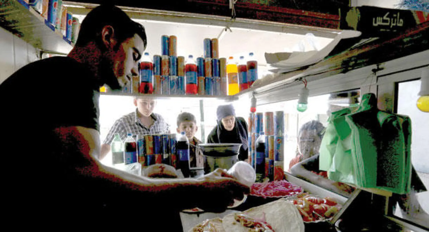 سوريون لاجئون في مخيم الزعتري بالمفرق شمال الاردن، يشترون الطعام اول أيام عيد الفطر (رويترز)