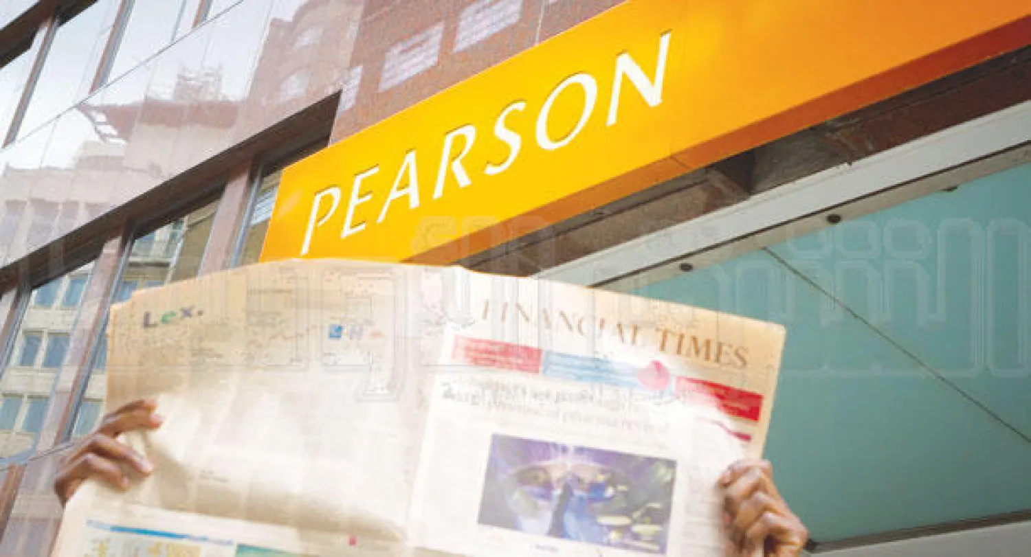 قارئ لـ«فاينانشال تايمز» أمام مقر «بيرسون» وسط لندن أمس (تصوير: جيمس حنا)