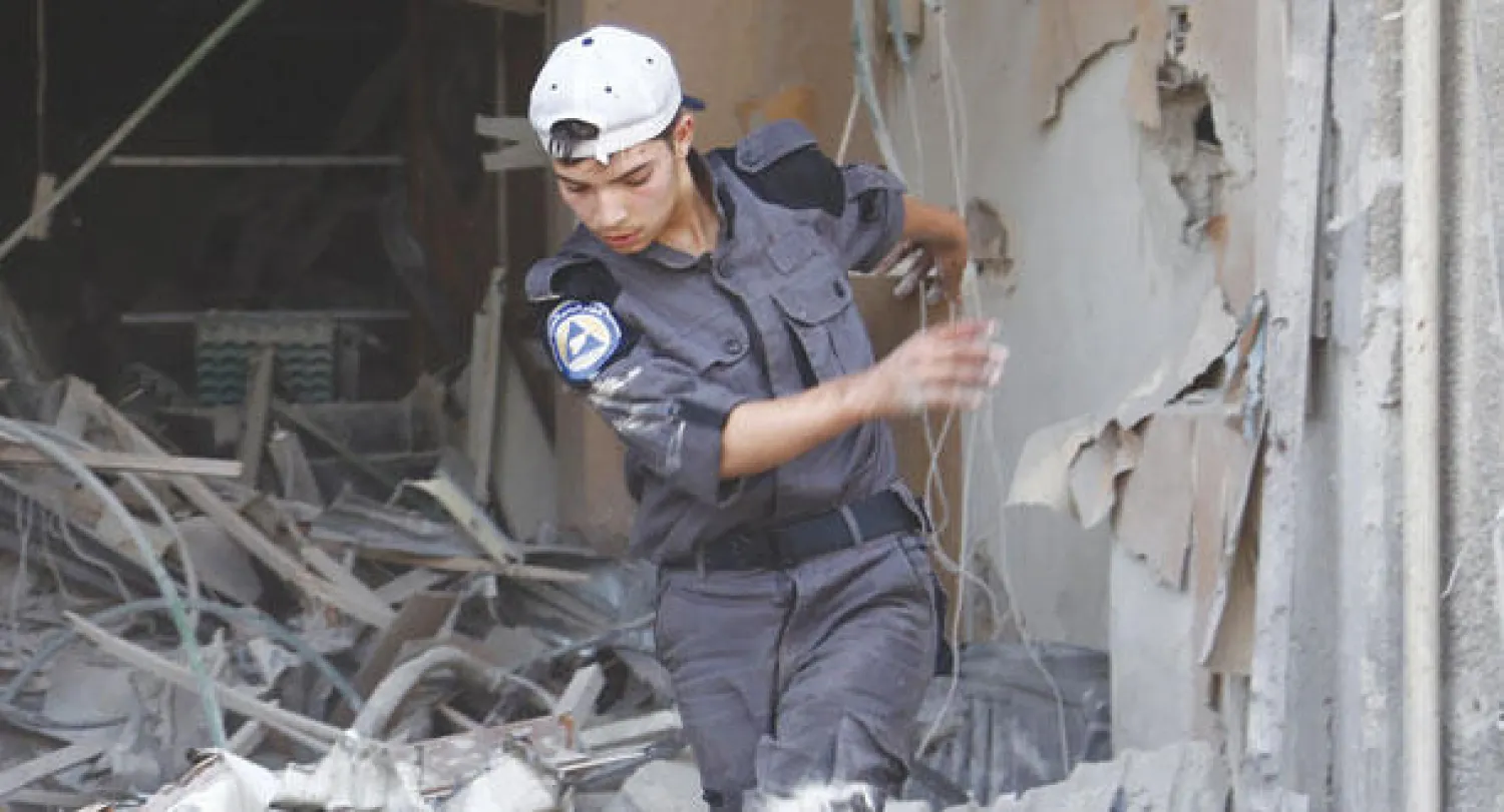 عنصر من الدفاع المدني في دوما بريف دمشق يبحث عن ضحايا بين ركام البناء الذي قصف بغارة جوية من طيران النظام السوري أمس (إ.ف.ب)