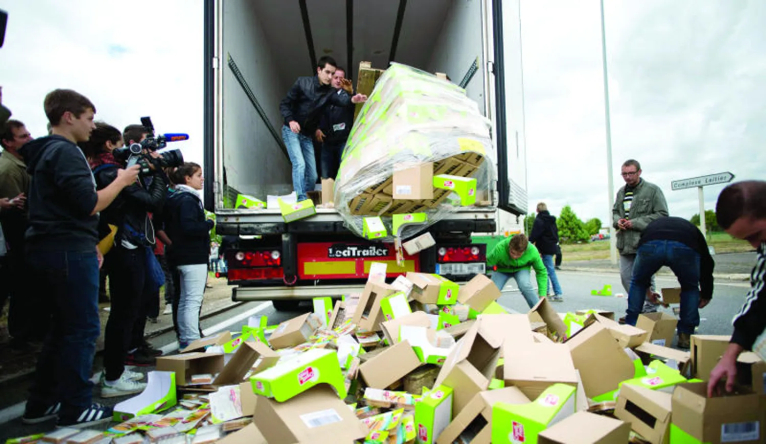 مزارعون فرنسيون يفرغون شاحنة من حمولتها من الفاكهة والخضار على أحد الطرق الرئيسية في إطار احتجاجاتهم على خفض اسعار منتجاتهم (أ.ف.ب)