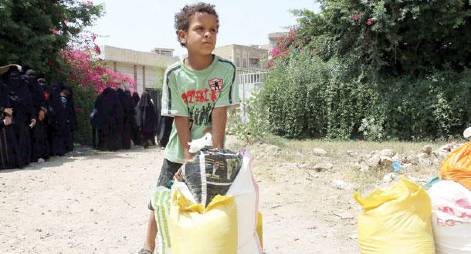 طفل يحمل مساعدات غذائية وزعت في تعز (إ.ب.أ)