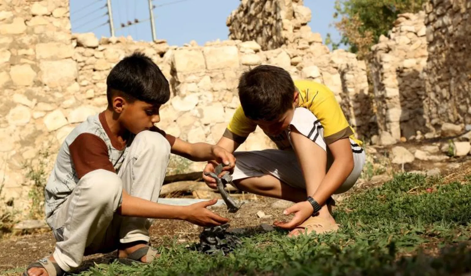 طفلان يلعبان بقطع معدنية هي بقايا صاروخ ألقته الطائرات الحربية التركية لضرب مقاتلي الـ«بي كيه كيه» حزب العمال الكردستاني في مدينة العمادية قرب دهوك شمال العراق (رويترز)