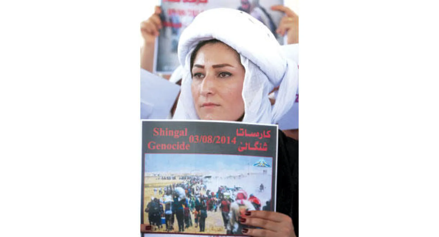 إيزيدية ترفع لافتة خلال مظاهرة أمام مكتب الأمم المتحدة في أربيل أمس (أ.ف.ب)