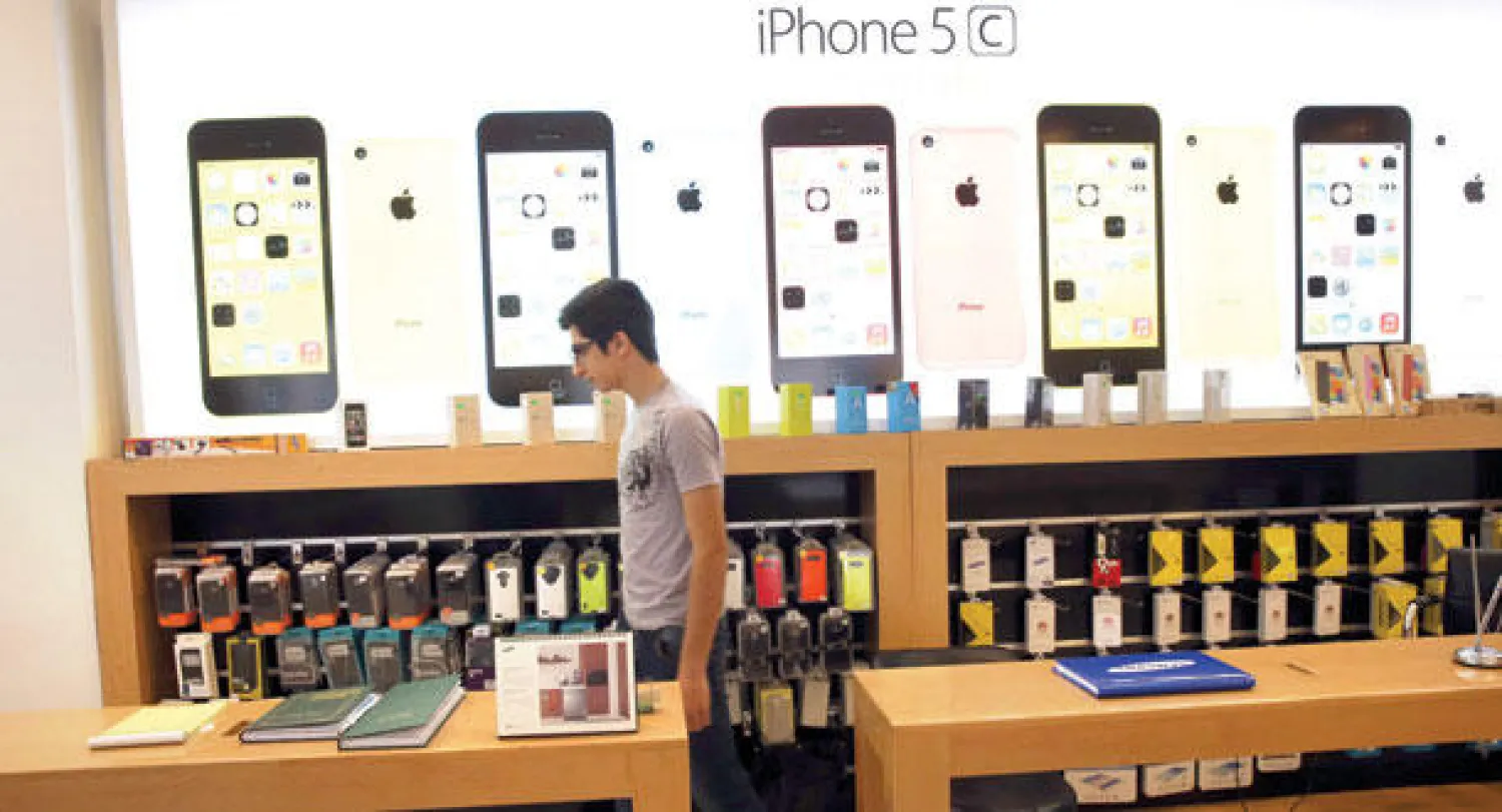 أحد الباعة يتجول في محل مختص ببيع هواتف الجوال (أبل) في طهران أول من أمس (أ.ب)