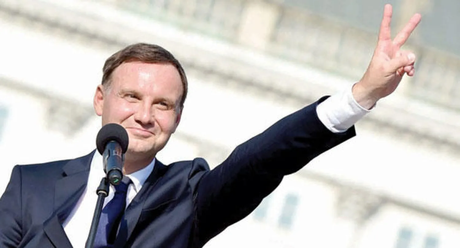 الرئيس البولندي الجديد اندري دودا يرفع علامة النصر أمام القصر الجمهوري في وارسو أمس (إ.ب.أ)