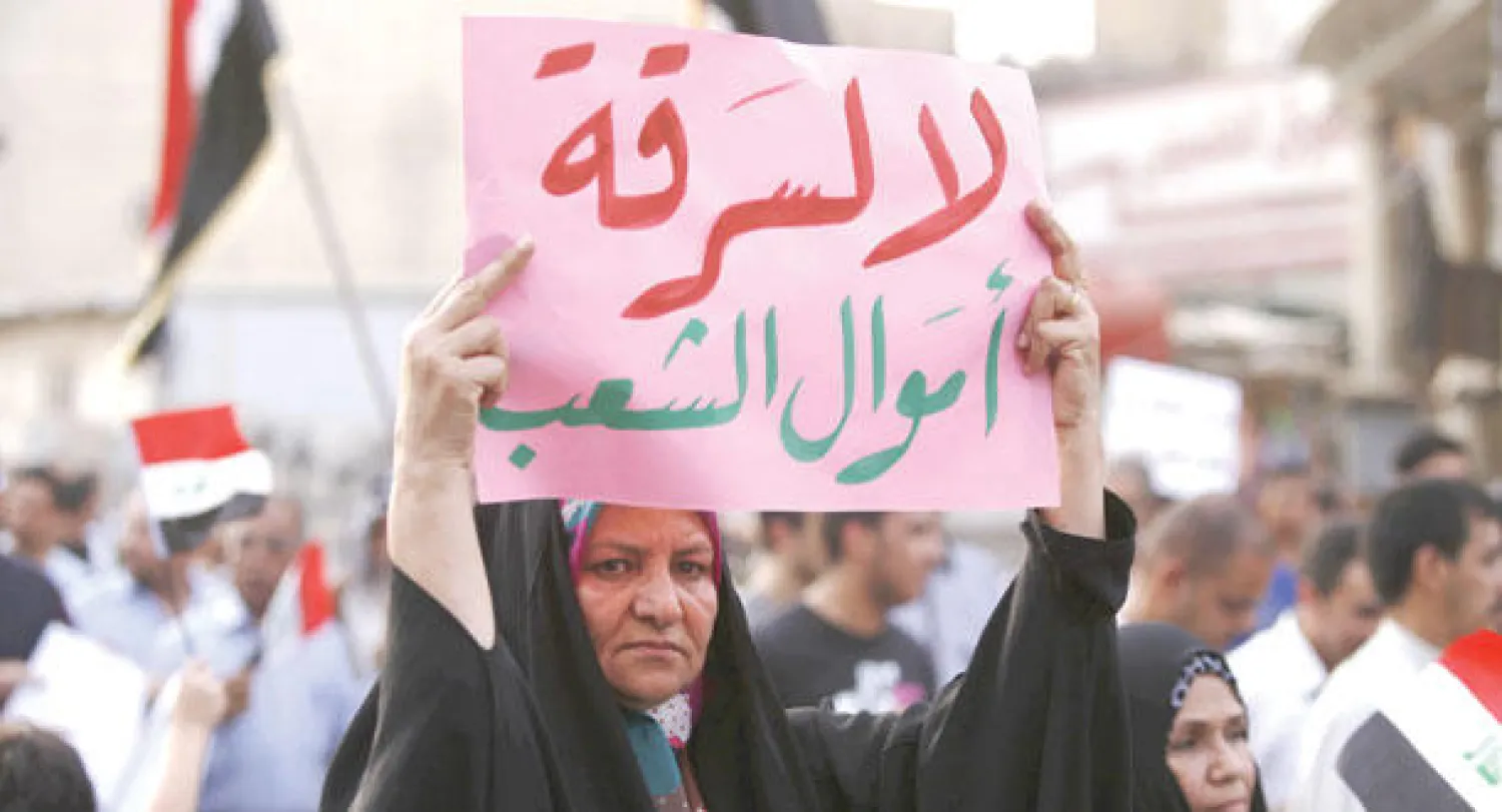 عراقية ترفع لافتة في مظاهرة ضد الفساد بمدينة كربلاء أمس (أ.ف.ب)