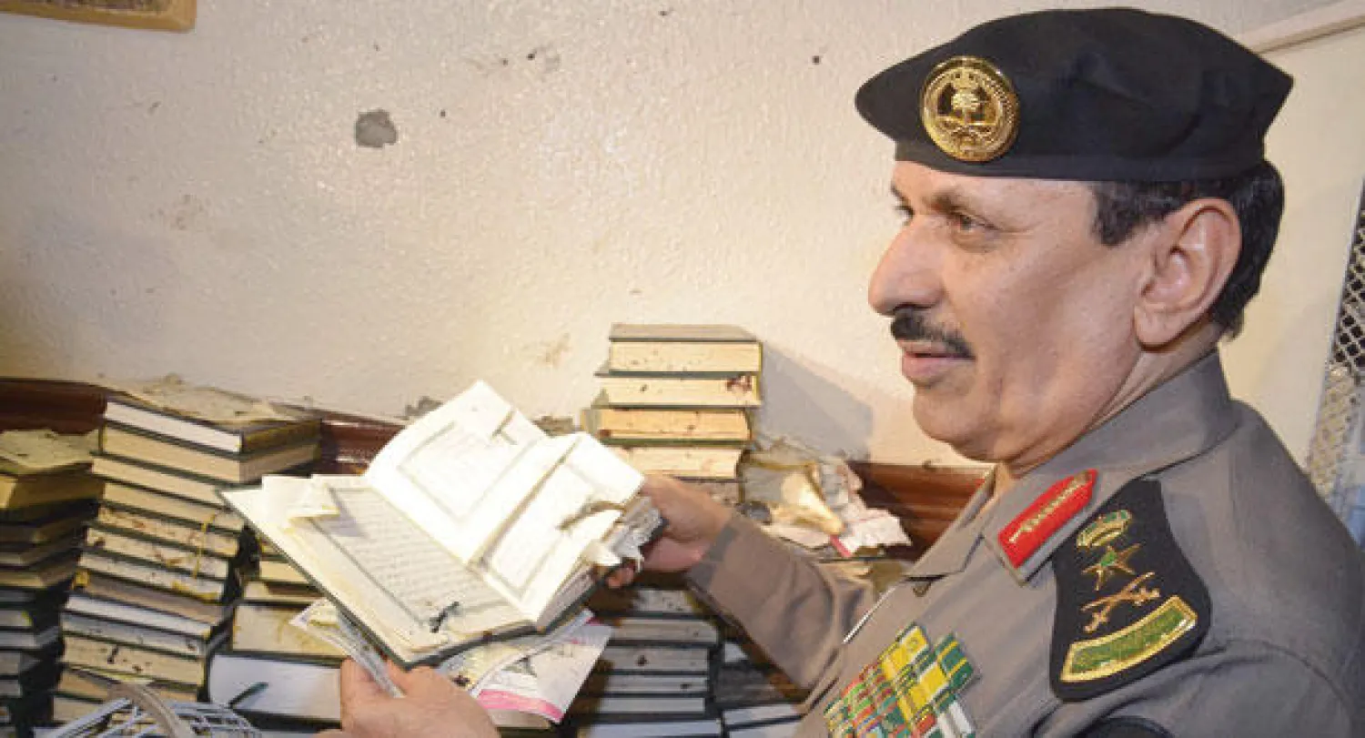 مدير الأمن العام يمسك بمصحف تسبب التفجير الانتحاري في تمزقه (واس)