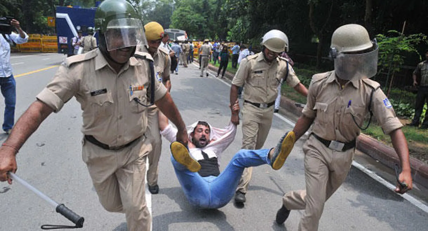 رجال الشرطة في دلهي يلقون القبض على أحد المحتجين على قرار تعليق عضوية 25 من نواب المعارضة بالبرلمان الهندي (غيتي)