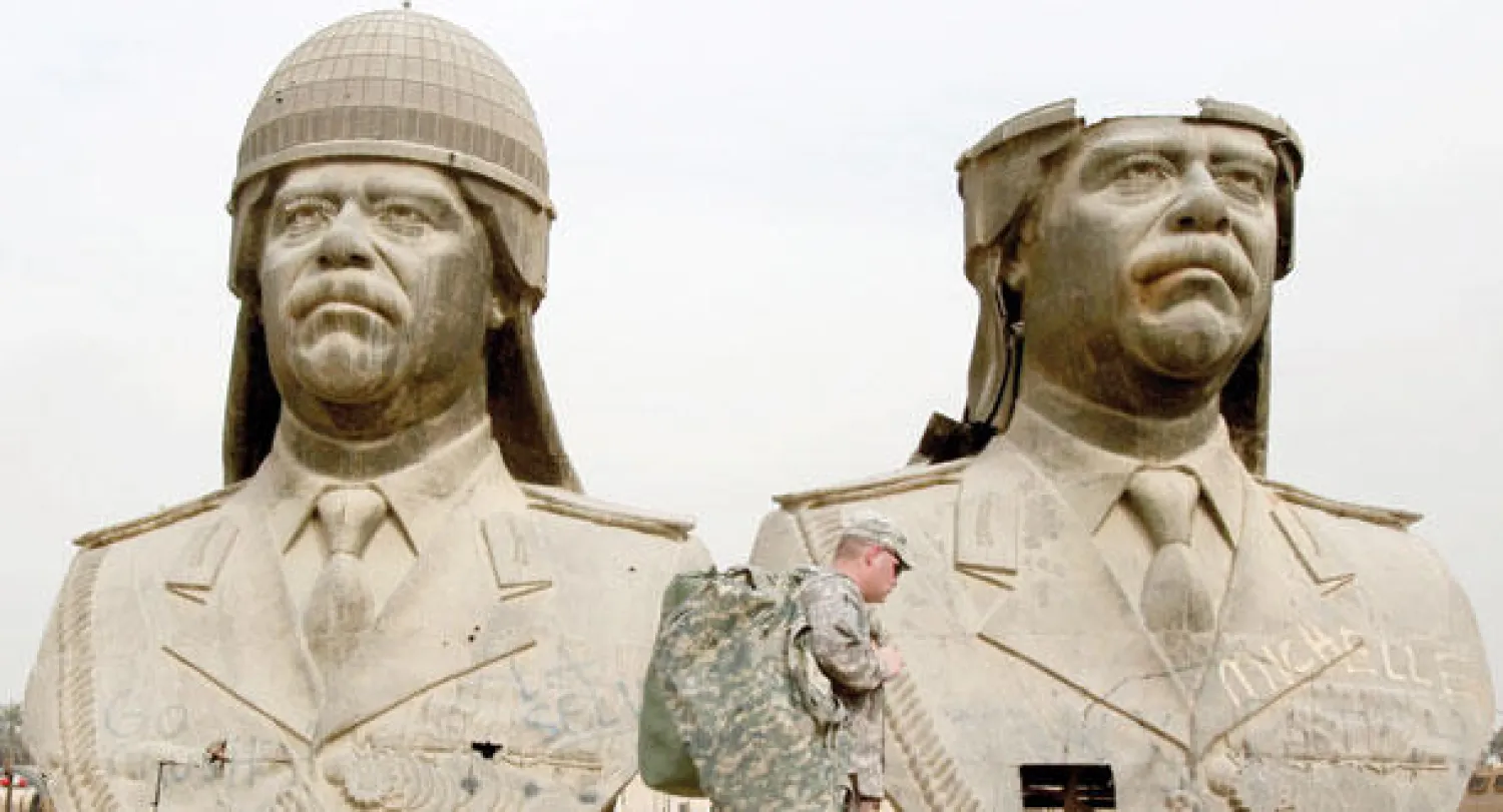 جنديان أميركيان يمران أمام تمثالين عملاقين من البرونز للرئيس العراقي السابق صدام حسين في بغداد في 20 مارس 2009 (أ.ب)
