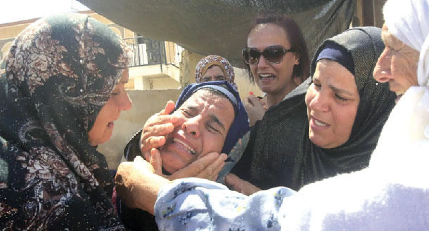 قريبات الدوابشة الأب والابن يبكينهما أمس في قريتهما دوما بالضفة الغربية (رويترز)