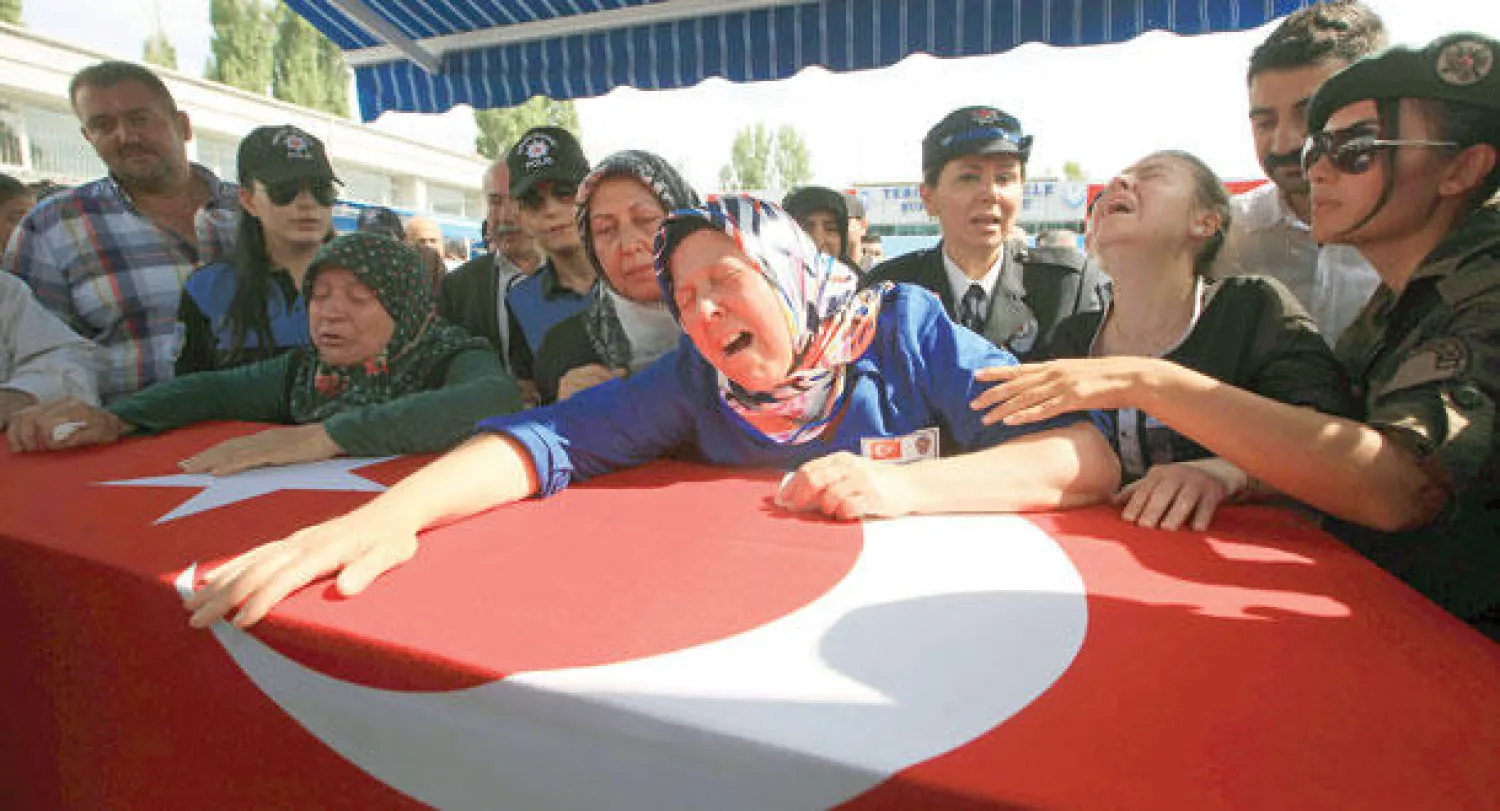 والدة العسكري التركي ساهين بولات آيدن الذي قتل في الهجوم على المروحية تبكي فوق نعشه المسجى في أنقرة أمس (أ.ف.ب)