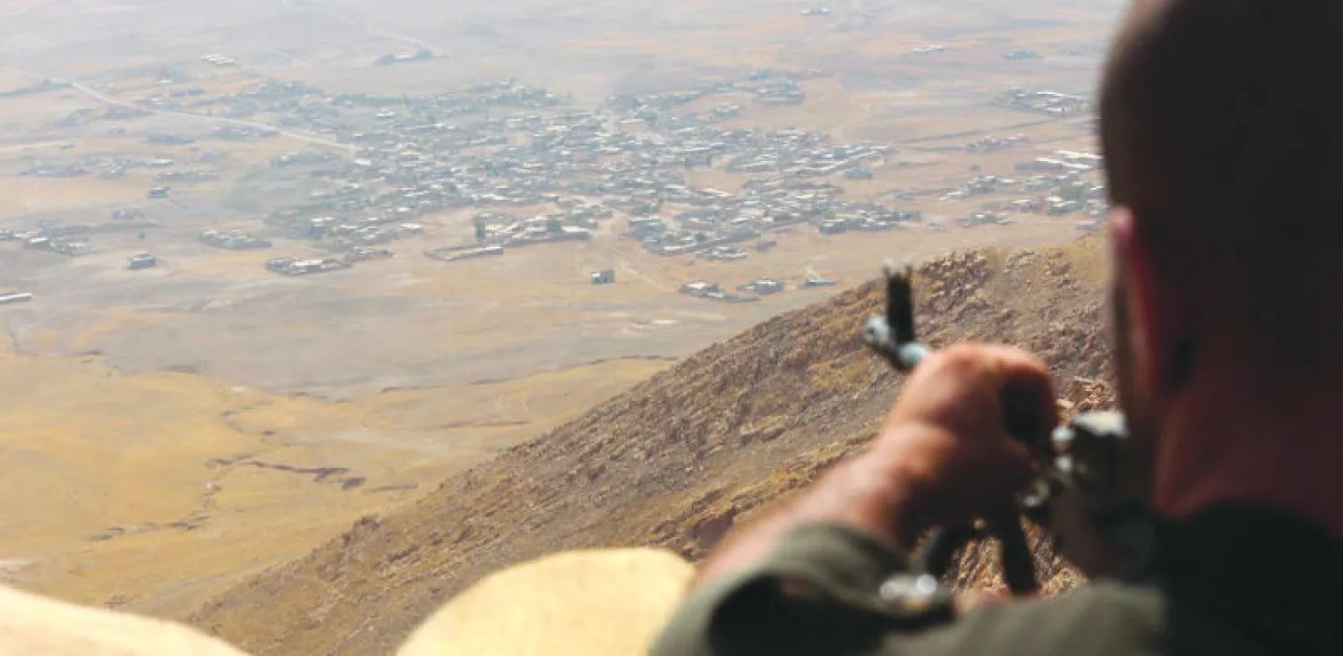عنصر في البيشمركة يطل من موضعه فوق جبل زردك على قرية خاضعة لسيطرة {داعش} شرق الموصل (أ.ف.ب)