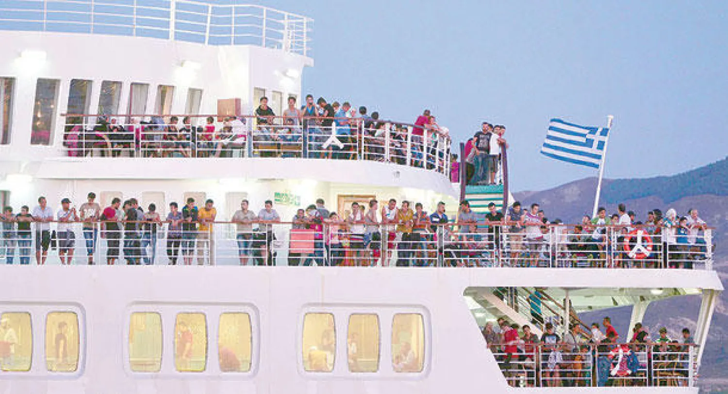 مهاجرون سوريون غير شرعيين فوق عبارة بحرية بجزيرة كوس اليونانية بعد أن تم وضعهم فيها من قبل السلطات المحلية (إ.ف.ب)  