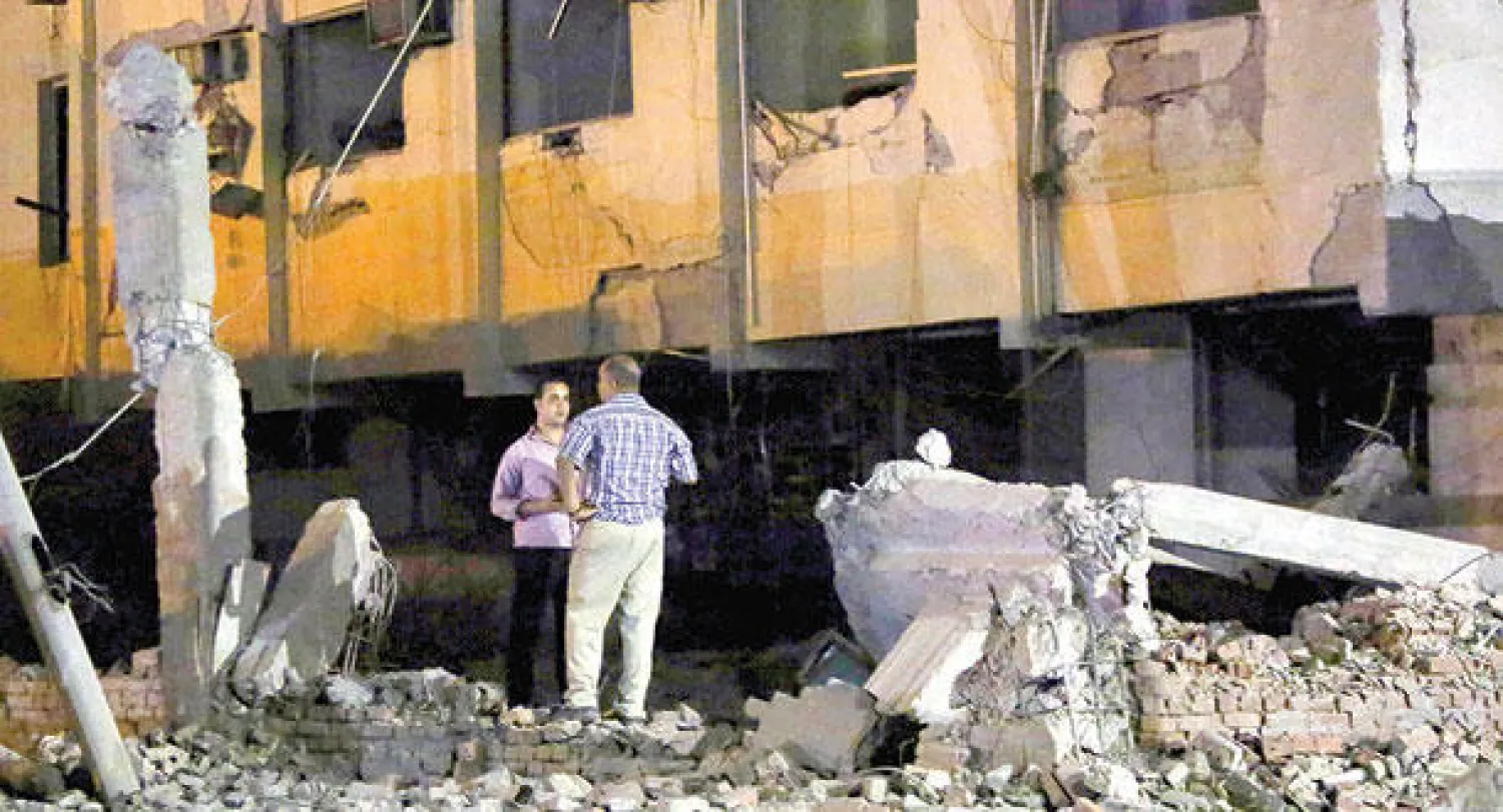 رجال أمن يعاينون آثار التفجير الذي استهدف مبنى للأمن الوطني المصري بحي شبرا الخيمة شمال القاهرة أمس (رويترز)