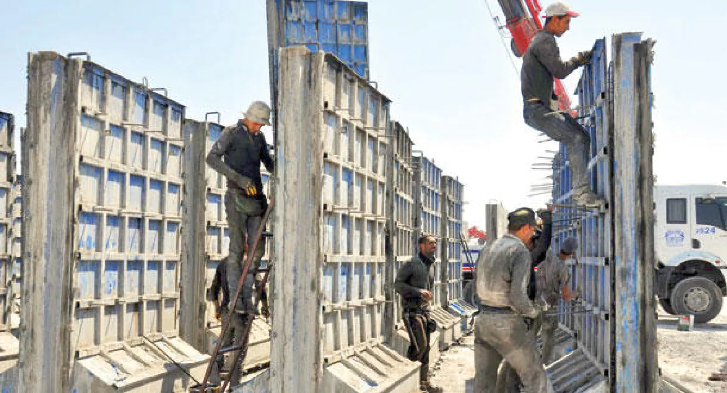 عمال بناء يشيدون سورا أسمنتيا في منطقة الريحانية الحدودية في محافظة هاتاي (الإسكندرونة) بجنوب تركيا لضبط الحدود مع سوريا ومنع تسلل الإرهابيين إليها (أ.ب)