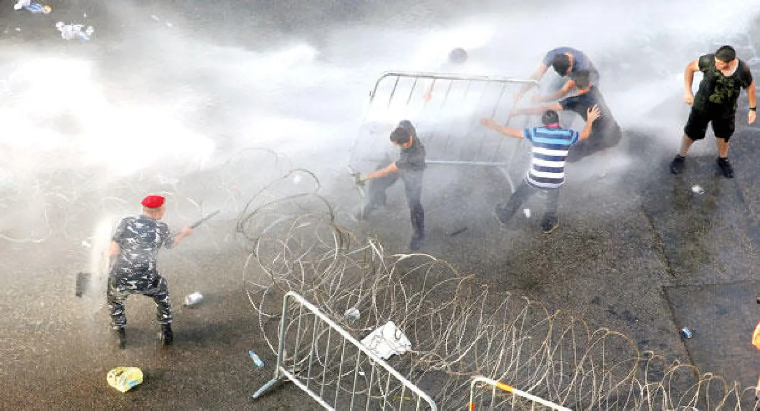 الأجهزة الأمنية اللبنانية تستخدم خراطيم المياه لتفريق نشطاء يحاولون إزالة الأسلاك الشائكة  التي تسد مدخل القصر الحكومي خلال مظاهرة احتجاج ضد أداء الحكومة اللبنانية وسط بيروت (أ.ب)