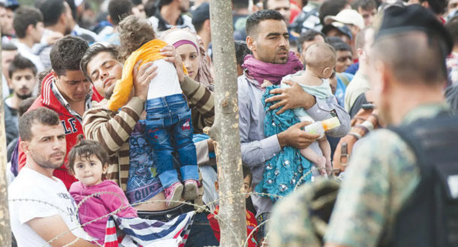 مهاجرون غير شرعيين ينتظرون عند الحدود المقدونية اليونانية أمس (أ.ف.ب)