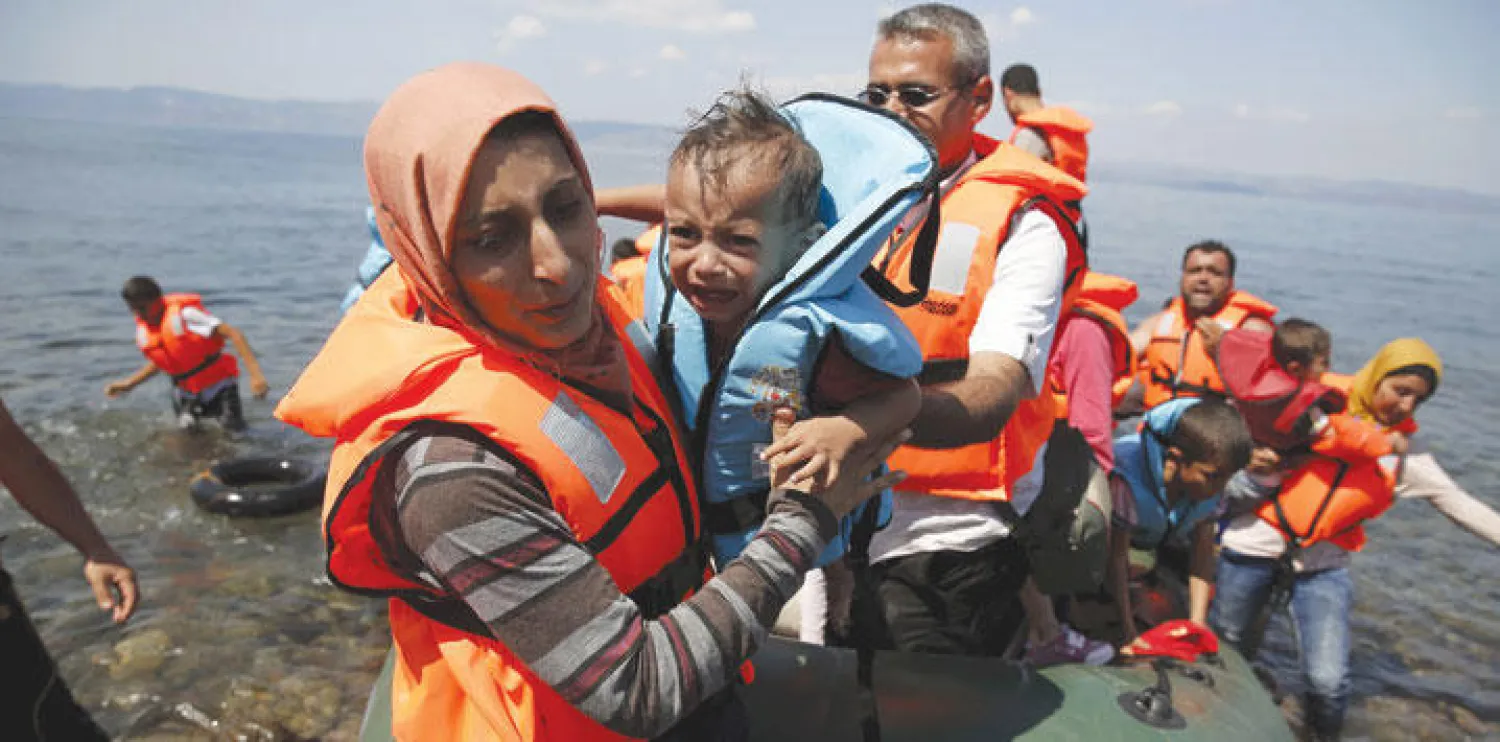 لاجئة سورية تصل إلى جزيرة ليسبوس اليونانية مع لاجئين آخرين على زورق صغير (رويترز)