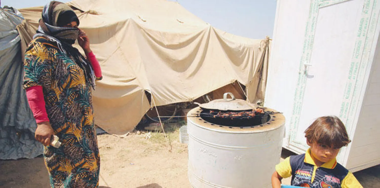 نازحة عراقية من الانبار تعد الطعام بمخيم في بغداد أمس (أ.ف.ب)