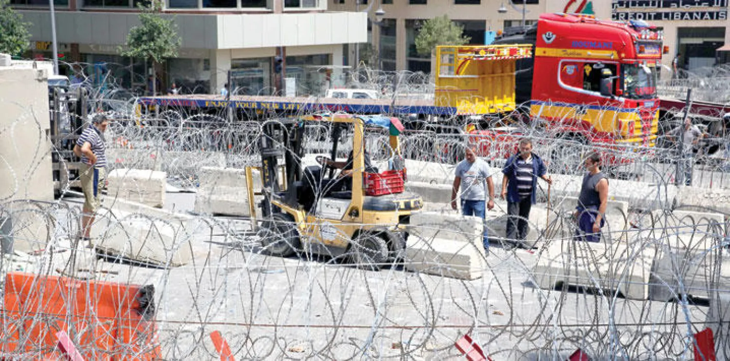 مهندسون يقيمون حواجز أمام القصر الحكومي في بيروت أمس، بعد أن تمت إزالة الجدار العازل الأخير، تحت الضغط الشعبي (أ.ب)